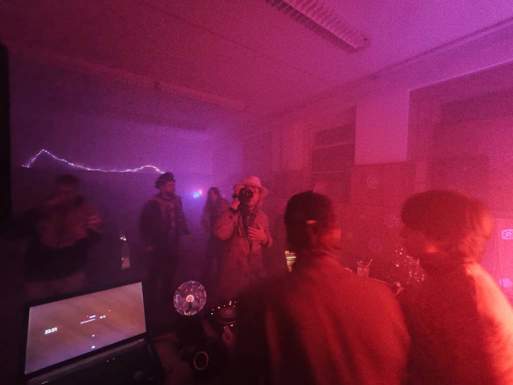 Dance Dancefloor view behind the DJ decks, also someone is recording the DJ table with an old-school camcoder