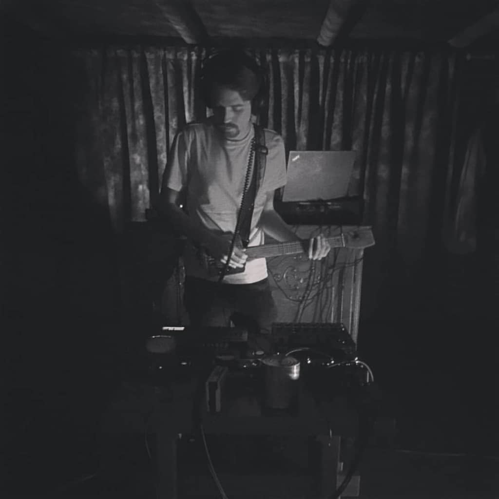 Dovydas playing the guitar Person playing a guitar with synths visible in the foreground