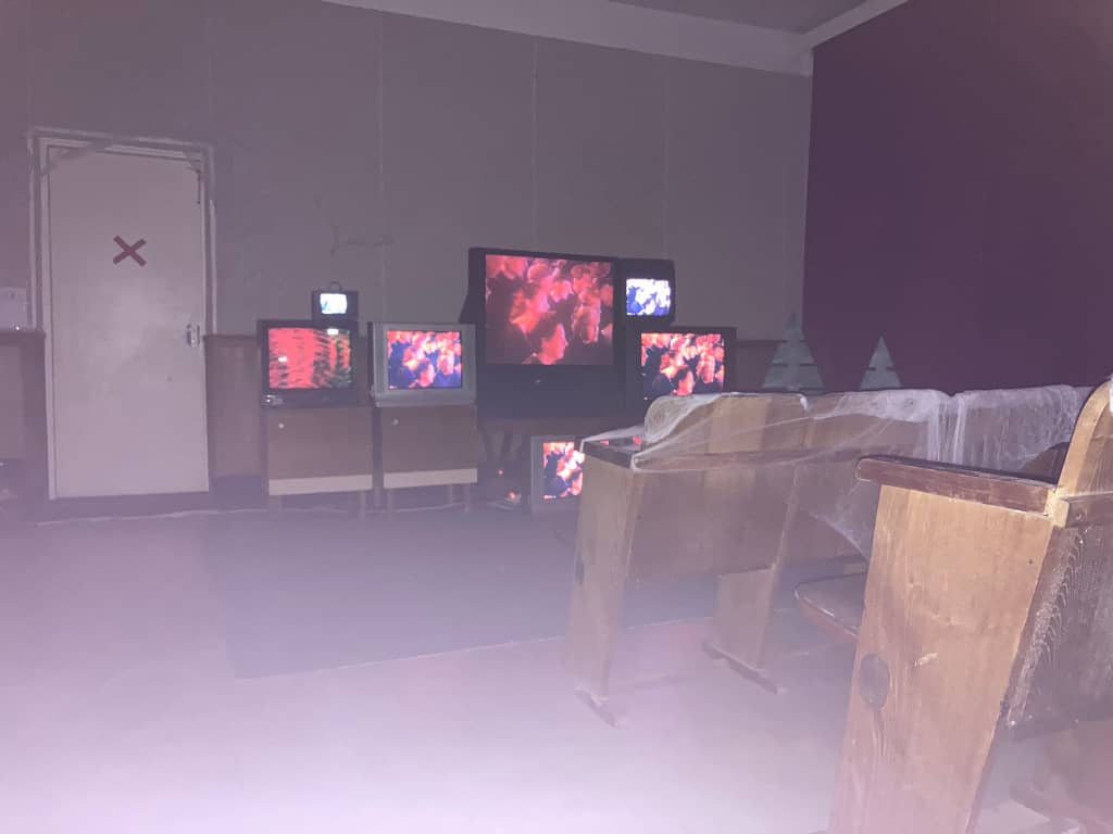 Spooky Cinema Array of old TVs stacked in front of old chairs