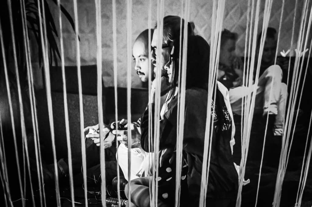 Gaming station Three people playing N64 games behind a wall of hanging wires