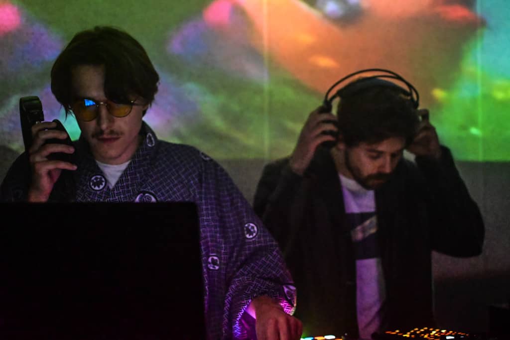 Main stage co-op Two performers at the main stage, video playing in the background from a projector