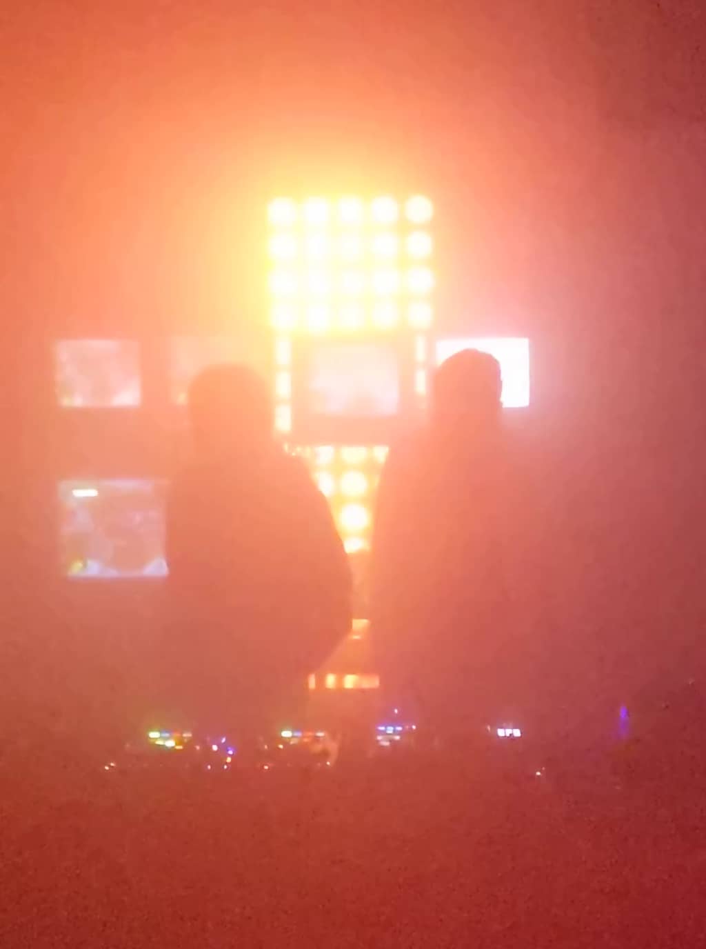 Performers Two performers lit by a bright light and TVs