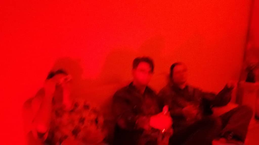 Red Room Three people sitting on a couch in room with overexposed red light